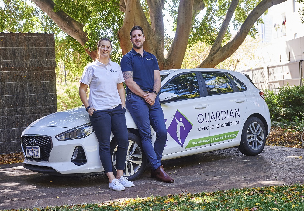 Two people stand next to a vehicle marked with a 
