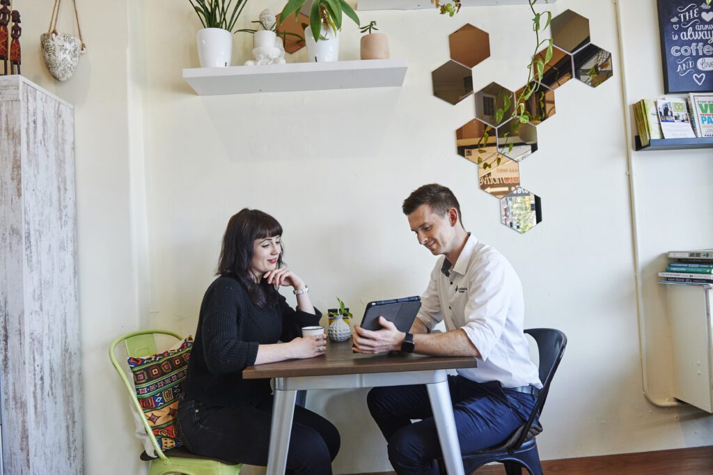 A man and woman sit at a cafe table, discussing opportunities in Guardian Exercise Rehabilitation for recent graduates.