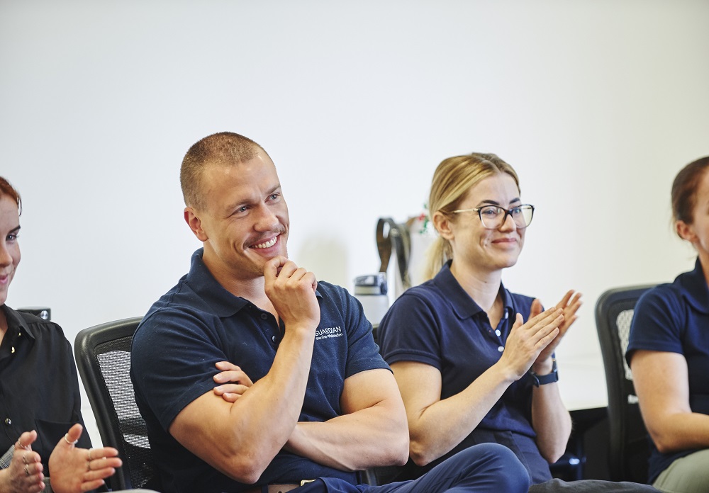 A diverse group of individuals seated in a room, hands clasped, engaged in a discussion about careers at Guardian Exercise Rehabilitation.