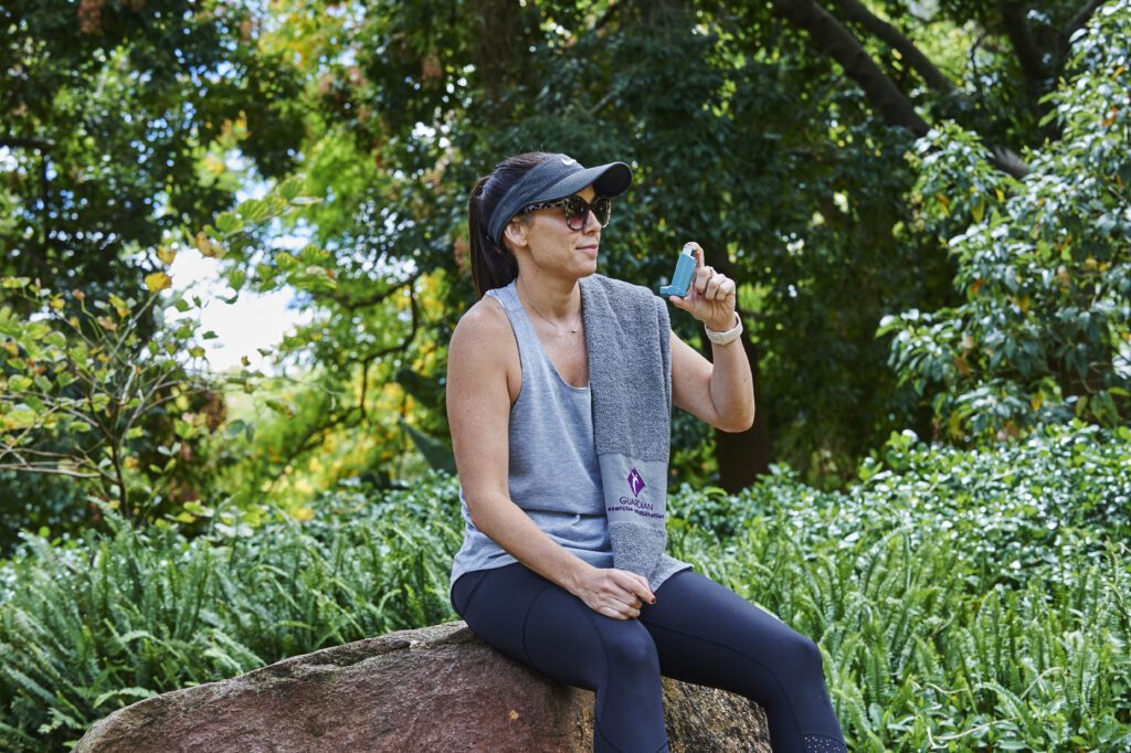 A woman sits on a rock in a park, enjoying nature, reflecting on health and wellness related to cardiovascular and respiratory conditions.